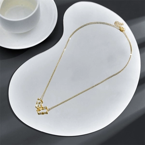 Minimalistische geometrische goldene Halskette mit strukturiertem Anhänger auf Tablett