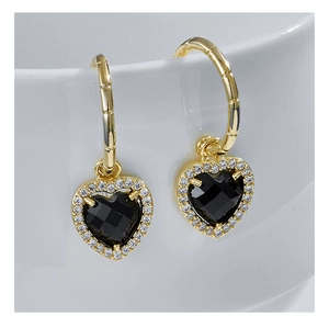 Detailed view of heart-shaped earrings with black gemstone and pavé diamonds on a cup