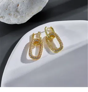 Dettaglio di orecchini a catena in oro 14k con zirconi lucenti e design a doppio anello