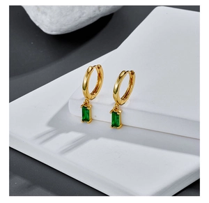 Macro shot of minimalist gold earrings with emerald green rectangular cut cubic zirconia
