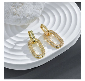Dettaglio degli orecchini in oro 14k con pendente geometrico e zirconi incastonati