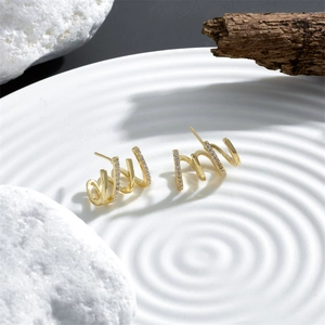 Macro detail of 18k gold spiral claw earrings with sparkling zircon inlay design