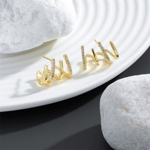 Detailed side view of golden four-claw earrings with micro-inlaid white zircons on a tray