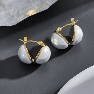 Detail of 14k gold baroque pearl hoop earrings on a textured grey background
