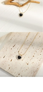 Détail d'un pendentif cœur noir avec zircons sertis sur une chaîne de collier dorée