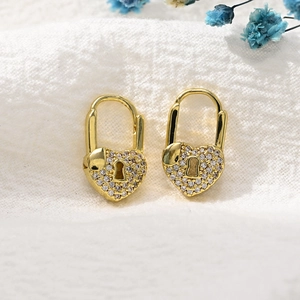 Macro detail of gold-plated heart padlock earrings encrusted with sparkling zircon stones