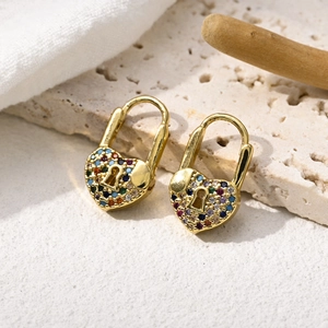 Golden heart lock earrings with colorful pavé zircons on natural stone background
