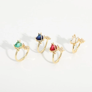 Detail of four colorful heart crystal rings with gold plating and star accents