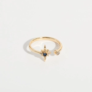 Detailed macro of 18K gold starburst ring featuring a blue crystal and pave setting