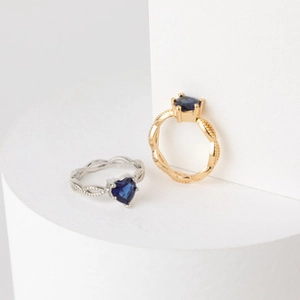 Close-up of gold and silver plated butterfly rings with blue heart gemstones on white stone