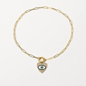 Detailed macro of gold paperclip chain necklace with heart zircon evil eye pendant