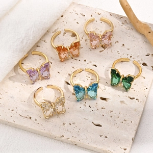 Detail showing various colors of butterfly crystal rings on stone and fabric background