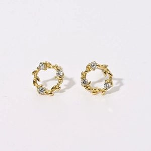 Gros plan de boucles d'oreilles dorées en forme de couronne avec motifs de feuilles et pierres