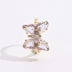 Macro detail of golden butterfly ring with purple crystal wings and diamond accents