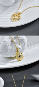 Detail of 14k gold plated heart evil eye pendant and baroque pearl on gold chain
