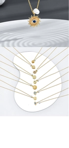 Macro detail of 14k gold plated evil eye and sun pendants with natural pearls