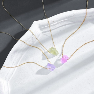 Detailed shot of gold plated necklaces with natural raw green, purple, and pink gemstones