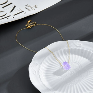 Detail of a minimalist 14k gold plated necklace with a natural purple raw stone pendant
