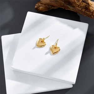 Boucles d'oreilles cœur dorées à l'or 14 carats sur des supports en pierre minimalistes