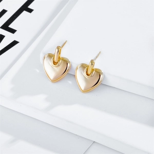 Vue détaillée de boucles d'oreilles cœur en or poli sur un support décoratif blanc
