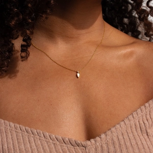 Detailed close-up of 14k gold teardrop necklace with zircon on elegant female neck
