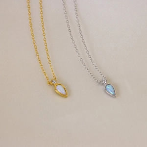 Macro detail of teardrop opal necklaces in gold and silver finishes with zircon accent