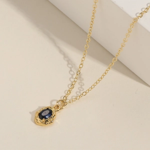 Collier géométrique doré avec pierre ovale bleu foncé et texture de lave unique
