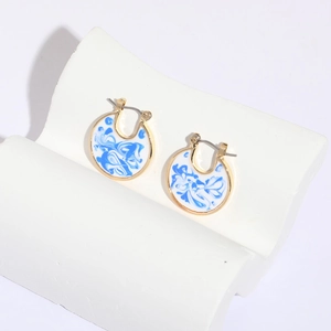 Blue porcelain enamel hoop earrings in 14k gold plating with artistic ink patterns