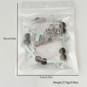 Detailed view of luminous cross pendants and black beaded chain set in packaging