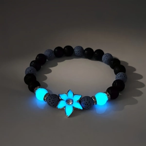 Charm de fleur lumineuse bleue brillant dans le noir sur bracelet en pierre de lave