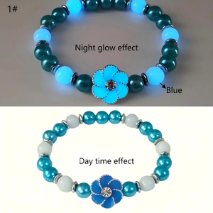 Close-up of blue beaded bracelet with flower charm showing day and night glow effects