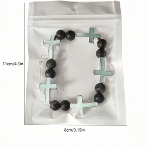 Detailed view of luminous cross bracelet with black lava stone beads in packaging