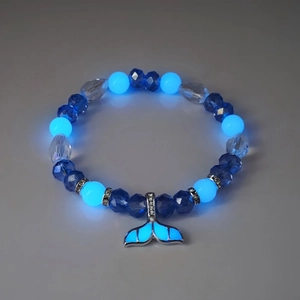 Macro detail van de walvisstaart hanger en lichtgevende blauwe kralen op armband