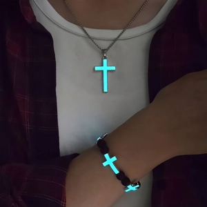 Luminous cross necklace and black lava bead bracelet set glowing in cyan blue