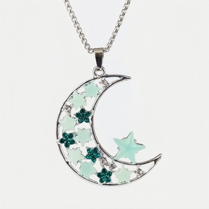 Silver crescent moon necklace with glowing stars and green rhinestones on white background