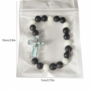 Charm croix lumineuse sur bracelet perles en pierre volcanique sous emballage