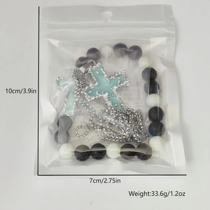 Détail du pendentif croix lumineuse et du bracelet en perles en sachet transparent