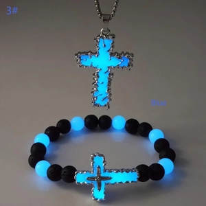 Détail macro du pendentif croix lumineuse bleue et de l'ensemble bracelet en pierre de lave