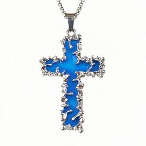 Gros plan du pendentif croix lumineuse avec résine bleue et texture de métal liquide