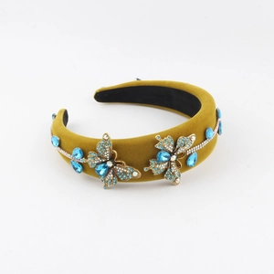 Détail d'un serre-tête en velours avec papillons dorés et strass bleus brillants
