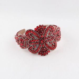 Détail d'un serre-tête en cristal rouge avec fleurs baroques en strass et doublure beige