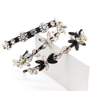Elegant woven headbands with crystal flowers and rhinestones on white geometric stand