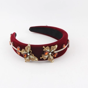 Détail du serre-tête en velours rouge avec papillons dorés et garniture de cristaux