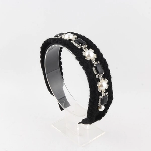 Détail d'un serre-tête en tricot noir avec perles blanches et strass étincelants