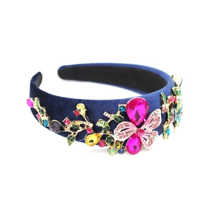 Detail of baroque headband featuring colorful crystals and butterfly on dark blue velvet
