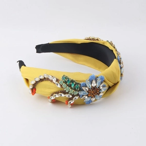 Detail of a yellow baroque headband featuring handmade beads and blue floral embroidery