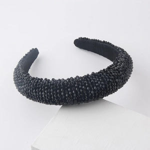 Detailed close-up of a black padded headband with shimmering crystal beads on white blocks