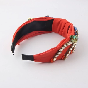 Detail of red fabric headband with colorful crystals, rhinestones and blue embroidery