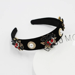 Detailed view of baroque headband with red gems and pearls on black velvet fabric