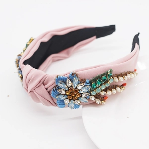 Detailed embroidery of sun flowers and sparkling rhinestones on a pink fabric headband